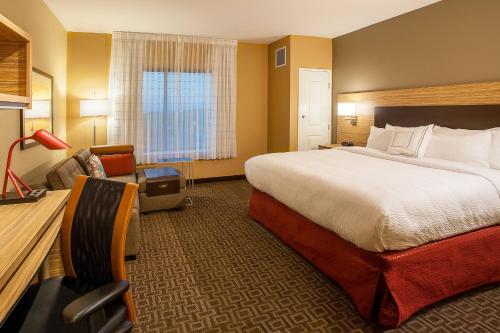 TownePlace Suites by Marriott Minneapolis near Mall of America في بلومنغتون: غرفة فندقية بسرير كبير وكرسي
