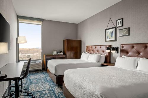 Westchester的住宿－Four Points by Sheraton Chicago Westchester/Oak Brook，酒店客房设有两张床、一张书桌和一个窗户。