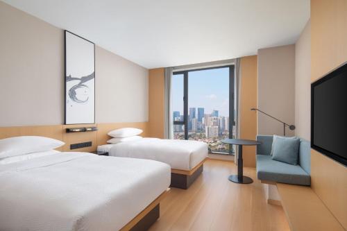 Fairfield by Marriott Chengdu Hi-Tech Zone في تشنغدو: غرفة فندقية بسريرين وتلفزيون بشاشة مسطحة