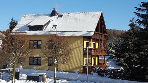 ein gelbes Haus mit einem schneebedeckten Dach in der Unterkunft Ferienwohnung für 6 Personen ca 100 m in Friedrichroda-Finsterbergen, Thüringen Rennsteig in Friedrichroda