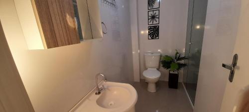 a white bathroom with a toilet and a sink at Excelente apto 501, apenas 5 min das Thermas in Piratuba