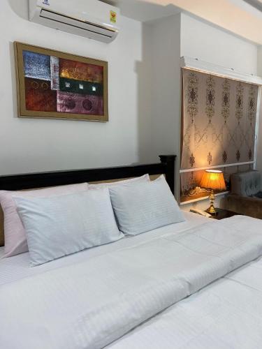 a bedroom with a white bed and a lamp at Century Premier Suite in Accra
