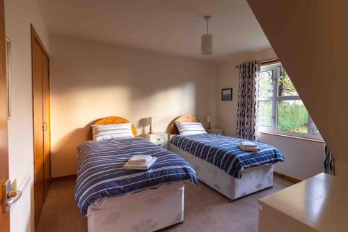 a bedroom with two beds and a window at Garden Cottage Helensburgh in Helensburgh