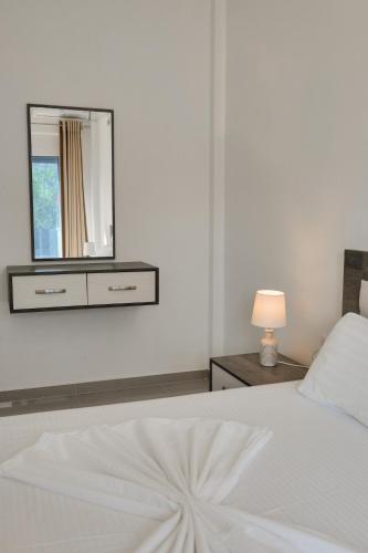 a bedroom with a white bed with a mirror on the wall at Fabeno Villa in Sarandë
