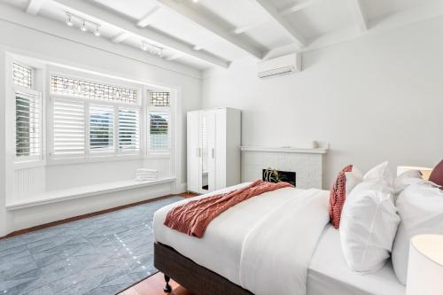 a white bedroom with a large bed and windows at Spacious Kingsland 4BR Home in Auckland