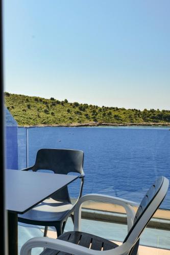 two chairs and a table on a balcony overlooking the water at Fabeno Villa in Sarandë