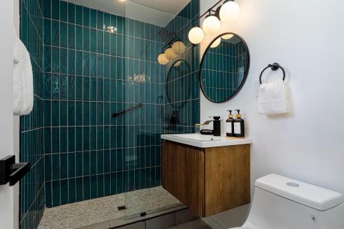 Baño de azulejos verdes con lavabo y aseo en Quail Park Lodge, en Kanab