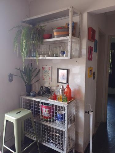 a kitchen with a shelf and a stool in a room at Quarto Aconchegante in Campos dos Goytacazes