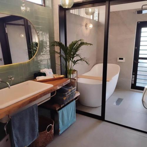 a bathroom with a tub and a large mirror at The Gold Beach House in Daisen