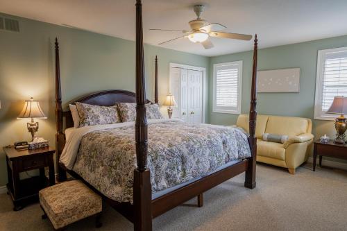 a bedroom with a canopy bed and a chair at Old Town Country Landing in Niagara on the Lake