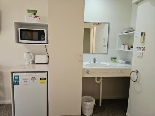 a small kitchen with a sink and a microwave at Alstonville Settlers Motel in Alstonville