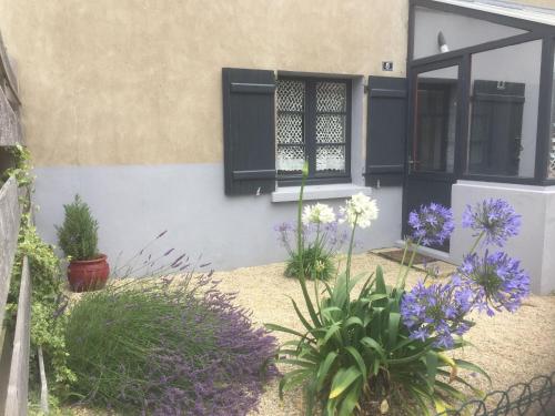 a house with black shutters and flowers in a yard at Gîte Charmant en Brière: Proche Guérande, Jardin Privé, 2 Chambres - FR-1-306-941 in Saint-Lyphard