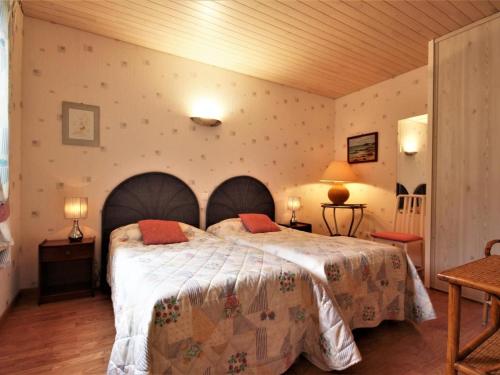 um quarto com uma cama grande e 2 almofadas laranja em Gîte La Turballe, 3 pièces, 4 personnes - FR-1-306-968 em La Turballe