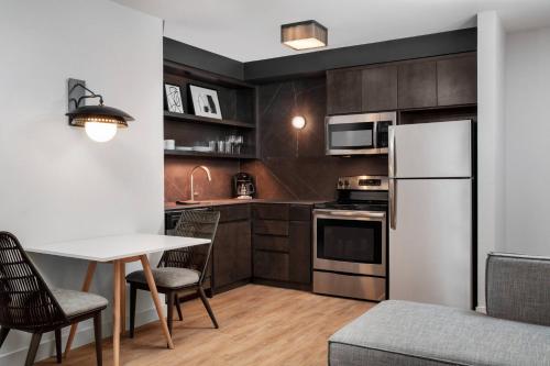 a kitchen with a table and a white refrigerator at Residence Inn by Marriott Miami Aventura Mall in Aventura