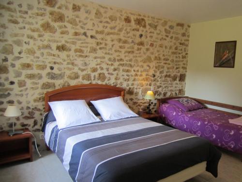 1 dormitorio con 2 camas y pared de piedra en Gîte Nohant-Vic, 4 pièces, 6 personnes - FR-1-591-195, en Nohant-Vic