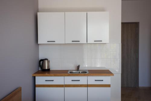 a kitchen with white cabinets and a sink at Planeta in Ustronie Morskie