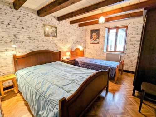 Laveline-du-HouxGîte rustique à Laveline-du-Houx, proche forêt - FR-1-589-141的一间卧室，有两张床和一堵砖墙