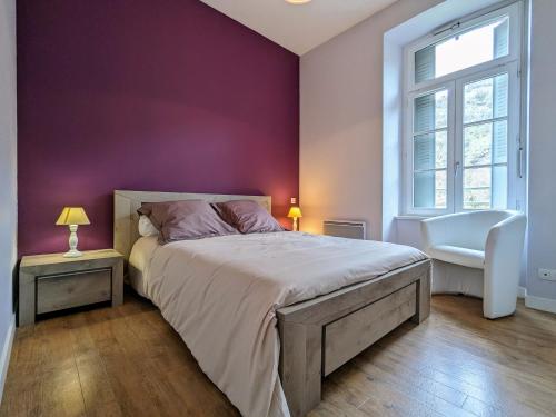 une chambre avec un lit et un mur violet dans l'établissement Gîte confortable 3 chambres au bord de l'Allier - FR-1-582-16, à Saint-Julien-des-Chazes