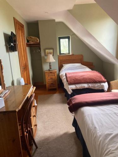 a bedroom with two beds and a dresser and a desk at Grove House Rooms in Cork