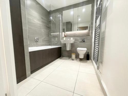 a bathroom with a toilet and a sink and a tub at 2 bedroom Apartment in Manchester