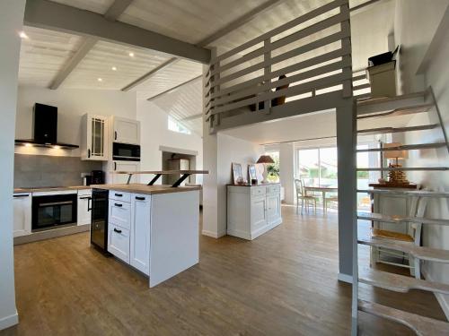 une grande cuisine avec des placards blancs et un escalier dans l'établissement Maison rénovée avec terrasse et jardin clos à 30m de la mer, parking, wifi - FR-1-306-1228, à Les Moutiers