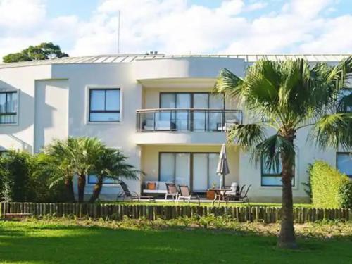 une maison blanche avec des palmiers devant elle dans l'établissement Flat Incrível - Livyd Angra dos Reis - Hotel do Bosque 3p, à Angra dos Reis