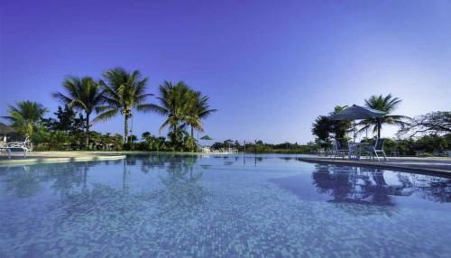 une grande piscine avec des palmiers en arrière-plan dans l'établissement Flat Incrível - Livyd Angra dos Reis - Hotel do Bosque 3p, à Angra dos Reis