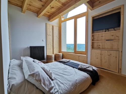 ein Schlafzimmer mit einem großen Bett und einem großen Fenster in der Unterkunft Gîte de Charme en Forêt: Nature, Confort, et Intimité Proche de Lyon et Clermont-Ferrand - FR-1-582-356 in Saint-Victor-sur-Arlanc