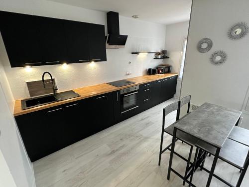 une cuisine avec des armoires noires et une table avec des chaises dans l'établissement Gîte 10 pers. avec jardin à 200m des commerces, proche Loire et forêt d'Orléans - FR-1-590-281, à Ouzouer-sur-Loire