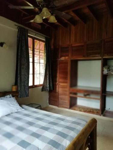 1 dormitorio con 1 cama con colcha blanca y azul a cuadros en Mountain Chalet, en Los Altos de Cerro Azul