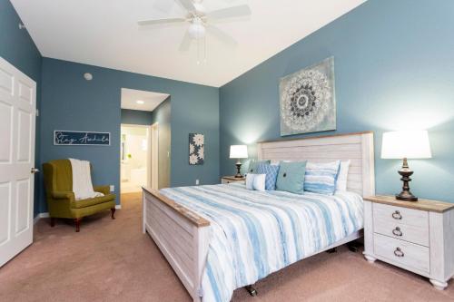 a bedroom with blue walls and a bed and a chair at Our Happy Place in Kissimmee