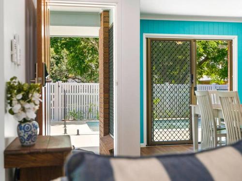 a screened in porch with a glass door with a table and chairs at Pet Friendly Spacious Home with Lush Gardens, Pool Sunshine coast in Pacific Paradise 