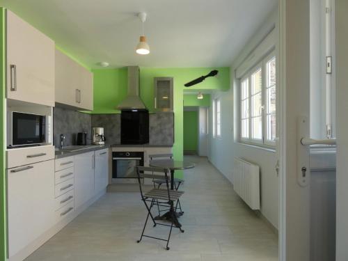 une cuisine avec des murs verts et une table et des chaises dans l'établissement Maison rénovée avec jardin, 3 chambres, à 10 min de Chartres, idéale pour familles et escapades romantiques - FR-1-581-114, à Thivars