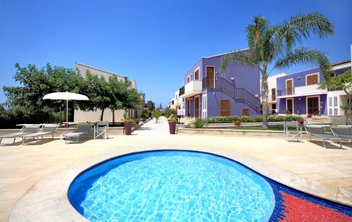 una piscina en un patio con sillas y un edificio en Blu ModicAmare, en Marina di Modica