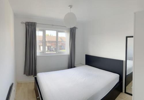 a white bed in a room with a window at Colliers Wood 1 Bed South London Short Stay in Mitcham