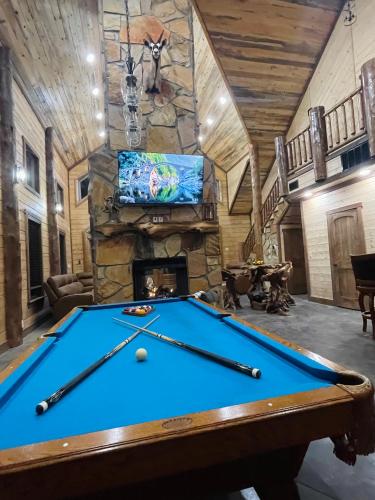 a pool table in a room with a fireplace at Wolf Creek Luxury Cabin in Broken Bow