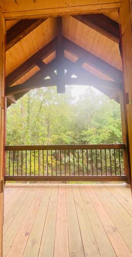 a large wooden deck with a view of the woods at Wolf Creek Luxury Cabin in Broken Bow