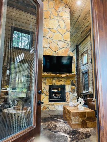 a living room with a stone fireplace and a television at Wolf Creek Luxury Cabin in Broken Bow
