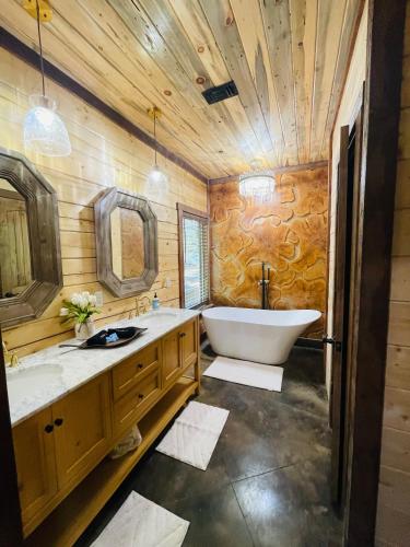 a wooden bathroom with a tub and a sink at Wolf Creek Luxury Cabin in Broken Bow