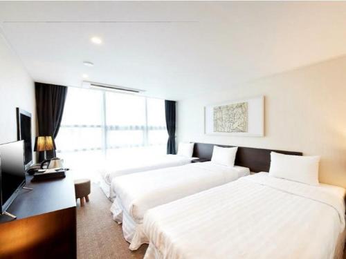 a hotel room with two beds and a television at Hotel K-Tree Pyeongtaek in Pyeongtaek