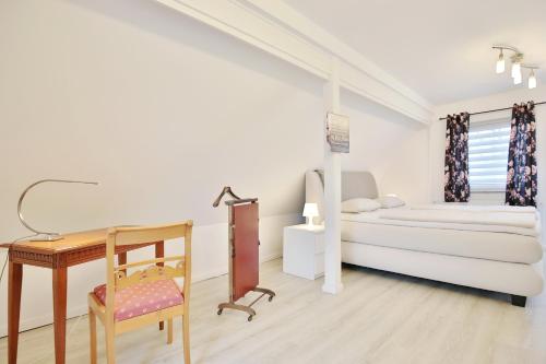 Un dormitorio blanco con una cama y un escritorio. en Haus Strandidyll Haus1, en Timmendorfer Strand