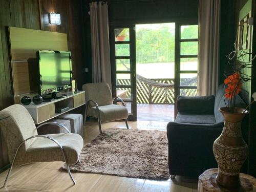 a living room with chairs and a tv and a couch at Casa de Campo Aconchegante in Quiriri