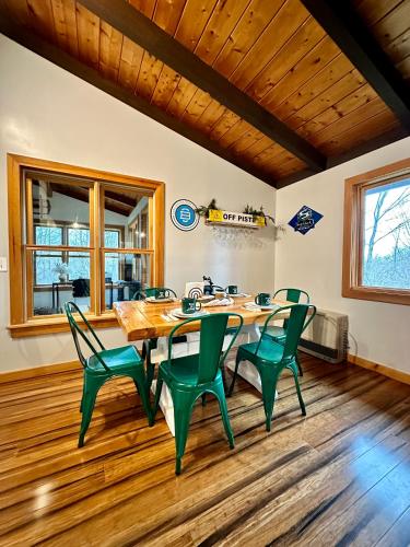 a dining room with a table and green chairs at Iron Gate Chalet - 5 Minutes to Smugglers Notch! in Cambridge