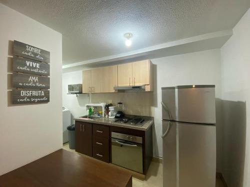 Una cocina con refrigerador de acero inoxidable y gabinetes de madera. en GIBRALTAR, en Manizales