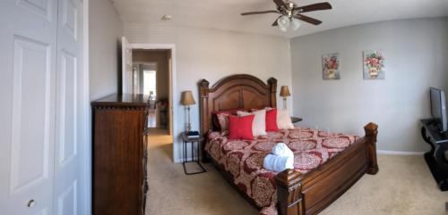 1 dormitorio con 1 cama con almohadas rojas y ventilador de techo en Townhouse near shopping/dining, en Winterville