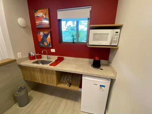 a kitchen with a sink and a microwave and a refrigerator at Flat Incrível - Livyd Angra dos Reis - Hotel do Bosque 5p in Angra dos Reis