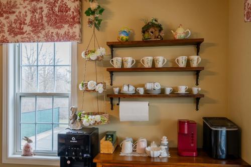 a room with shelves of tea cups and a window at Old Town Country Landing in Niagara on the Lake