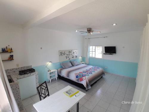 1 dormitorio con cama, mesa y TV en Claro de Luna, en Playa del Carmen