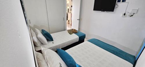 una piccola stanza con due letti e una televisione di APARTAMENTO ISLABLANCA PARQUE DEL CAFE MONTENEGRO a Montenegro