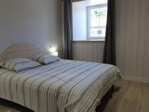 a bedroom with a bed with a striped blanket and a window at Gîte Arlempdes, 5 pièces, 8 personnes - FR-1-582-107 in Arlempdes